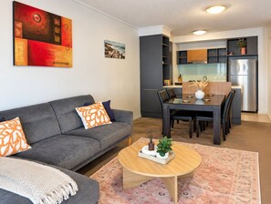 A modern living room with a sofa, coffee table, and dining area.