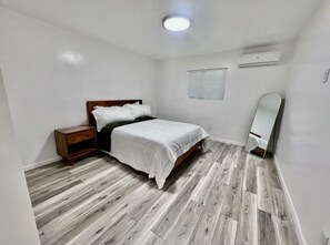 Ein Schlafzimmer mit Bett, Nachttisch, Spiegel und Deckenleuchte.