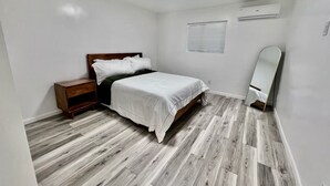 Ein Schlafzimmer mit Bett, Nachttisch, Spiegel und Deckenleuchte.