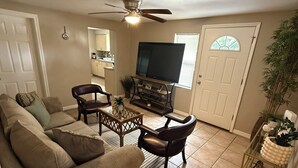 Un salon comprenant un canapé, des fauteuils, une table basse, un téléviseur et un ventilateur de plafond.
