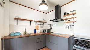 A modern kitchen with grey cabinets, wooden countertops, a built-in microwave, and a stainless steel range hood. - IslandHideaway Near Promthep Sunset V205 (Rawai)
