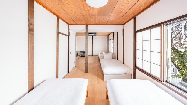 Une pièce avec un plafond en bois, deux lits, une fenêtre et une vue sur l’extérieur.