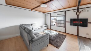 Un salon moderne avec un canapé gris, une table basse en verre et un plafond en bois.