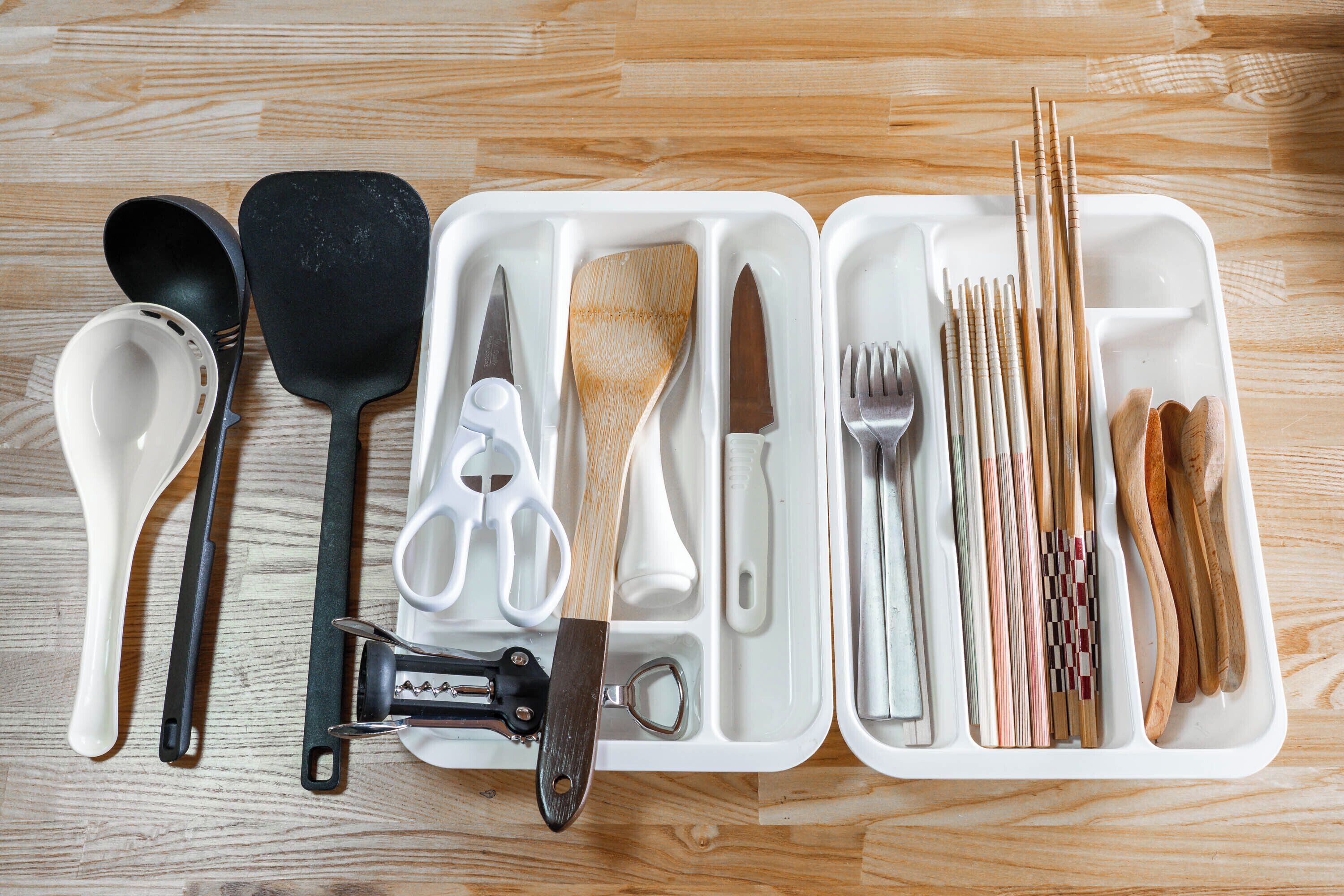 A set of kitchen utensils neatly arranged in a white tray with compartments.