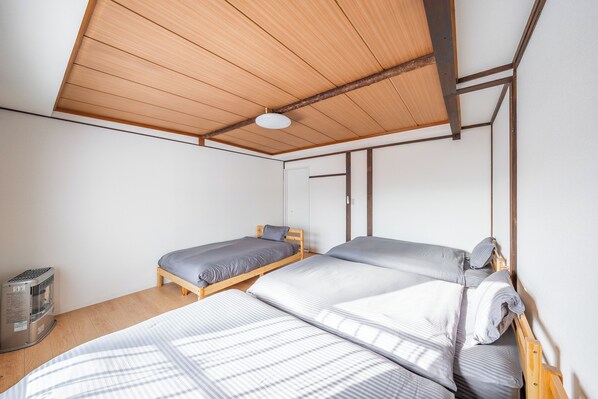 A room with two wooden beds, a ceiling fan, and a heater.