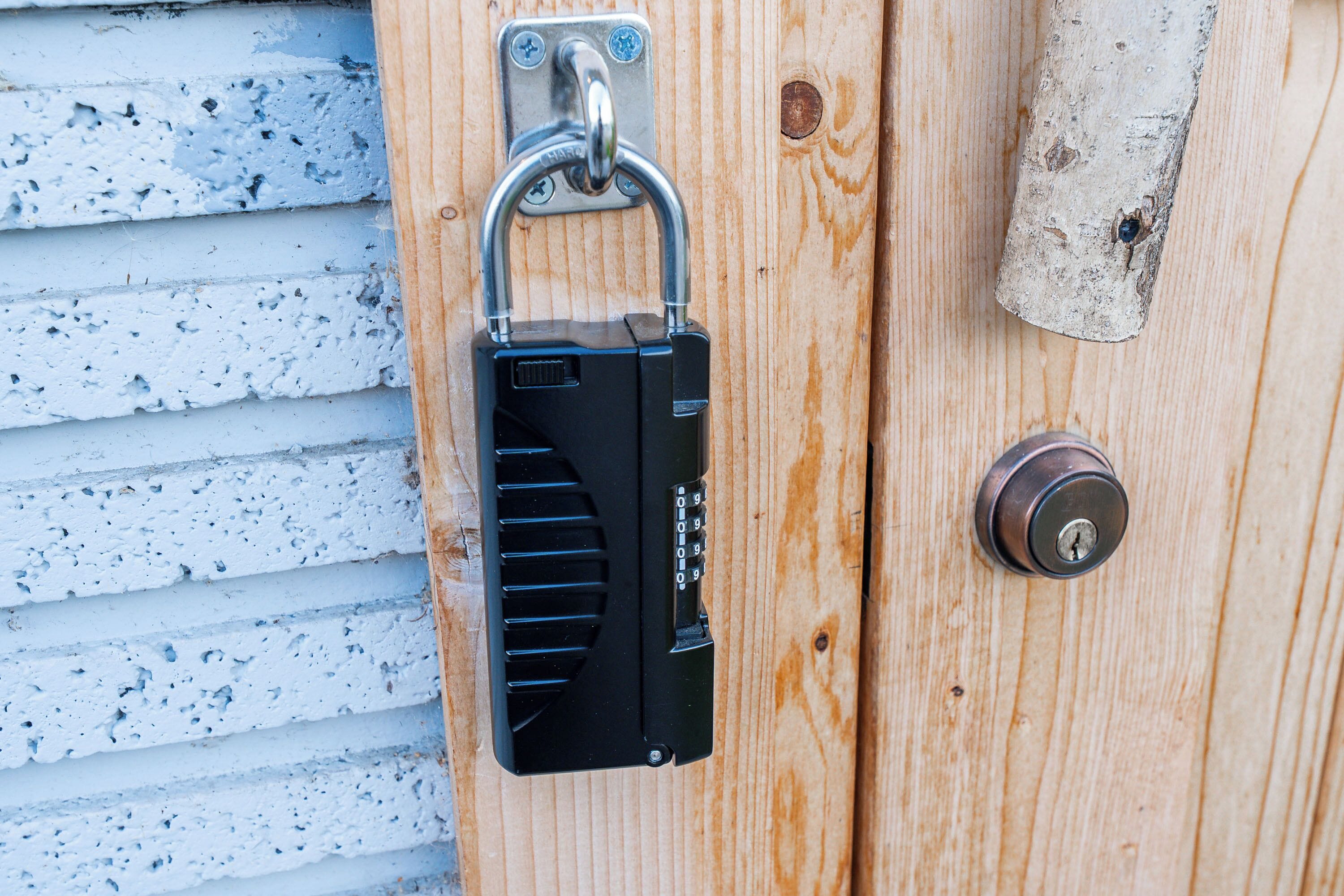 A padlock on a wooden door with a metal handle and a keyhole.