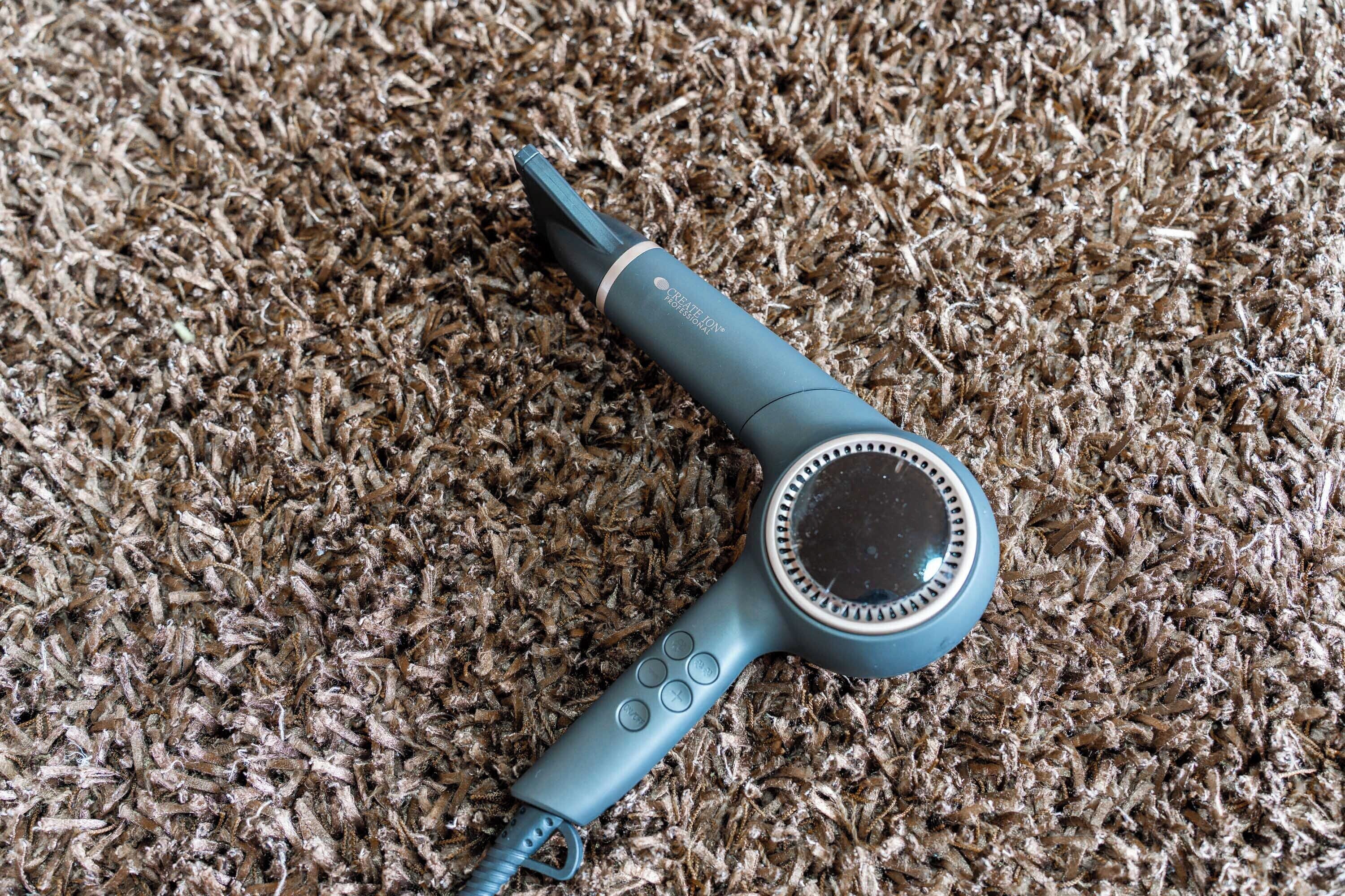 A hairdryer on a textured carpet.