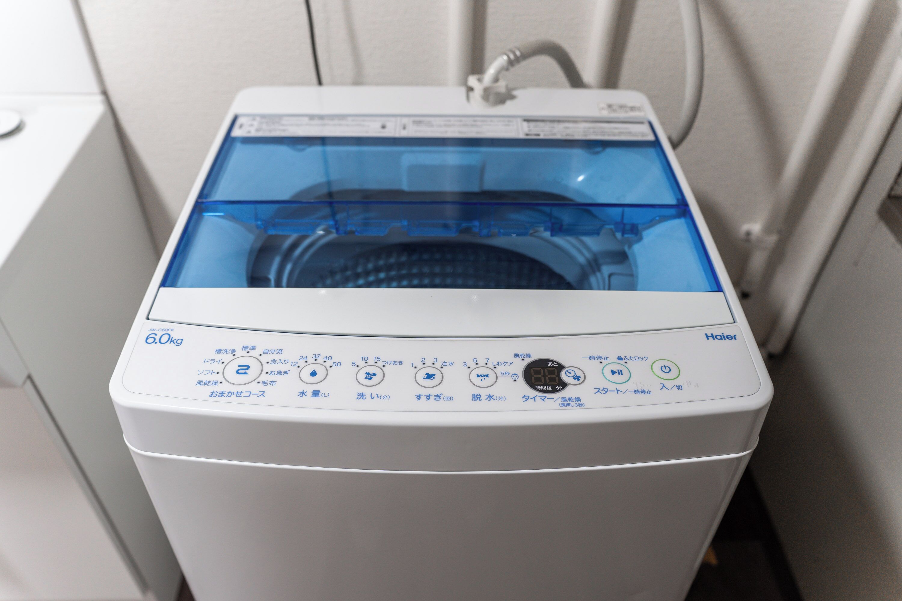 A front view of a white Haier washing machine with a digital display and multiple control buttons.
