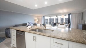 A modern kitchen with granite countertops, white cabinetry, and a stainless steel sink. - Charming 2-bedroom condo in fabulous Sanibel at Sundial (Sanibel)