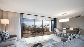 A modern hotel room with a balcony, a dining area, and a seating area with a sofa and chairs. - Charming 2-bedroom condo in fabulous Sanibel at Sundial (Sanibel)