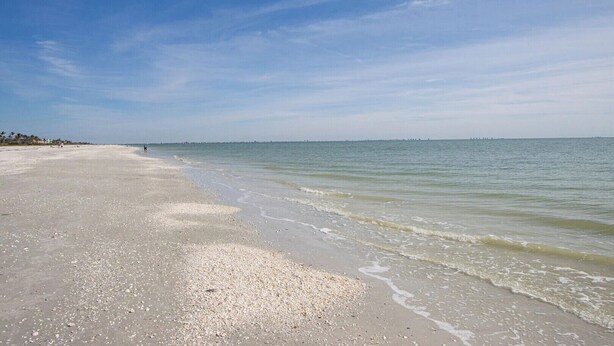A beach with a wide sandy shore and calm water. - Charming 2-bedroom condo in fabulous Sanibel at Sundial (Sanibel)