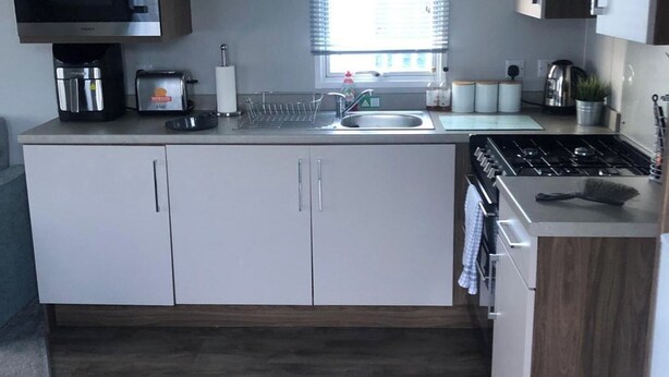A compact kitchen with a sink, stove, and cabinets.