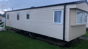 A mobile home with a single-story structure, a front porch, and a garage.