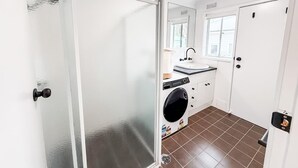A compact bathroom with a glass shower door, a sink, a washing machine, and a toilet. - 2/7 Halloran Street, Wagga Wagga (Wagga Wagga)