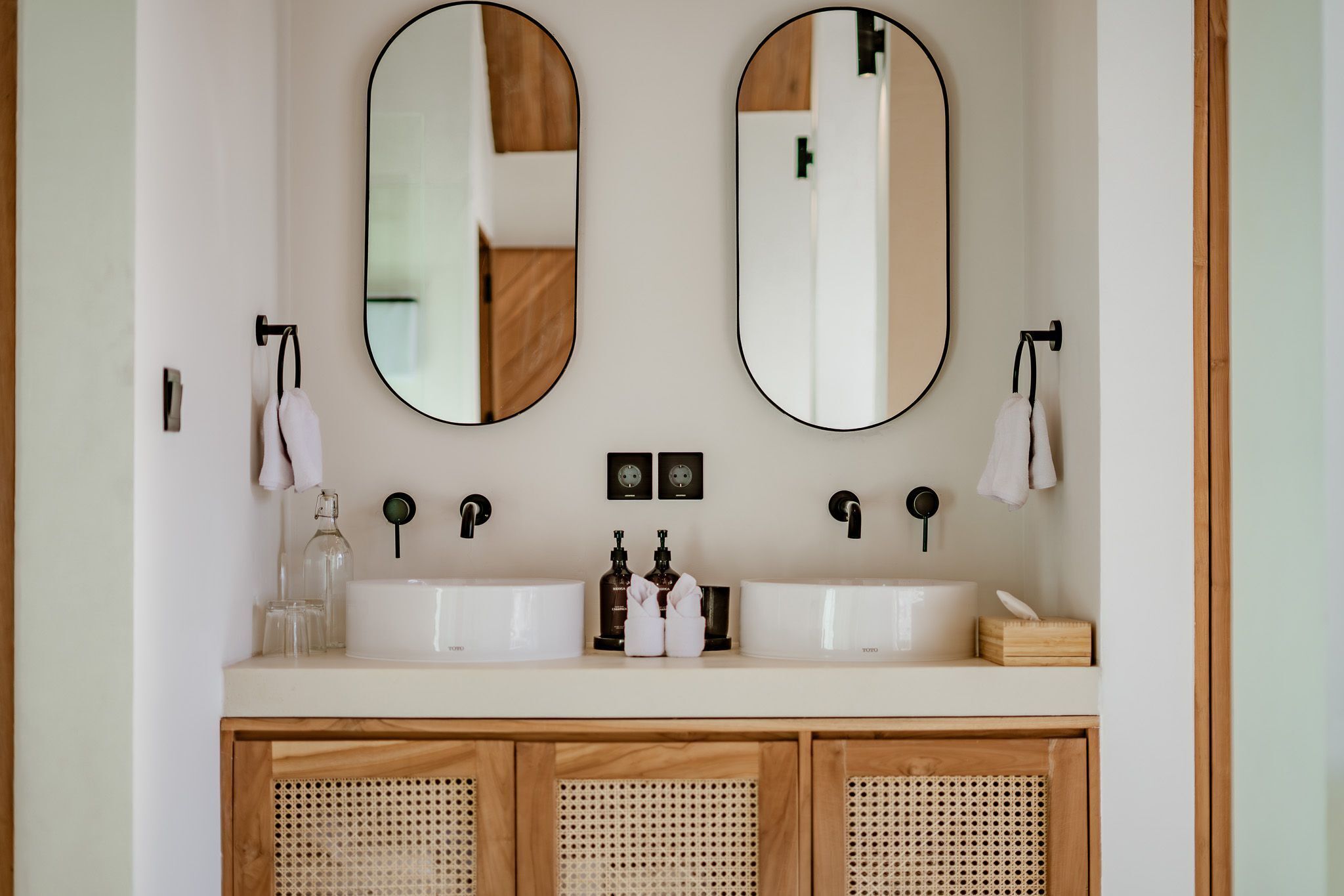 Une salle de bain avec deux miroirs, un lavabo double et un meuble en bois.