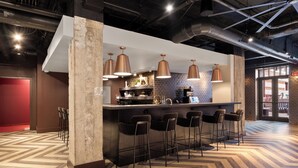A modern bar area with a herringbone floor pattern, a bar counter, and multiple bar stools. - Stylish Loft in St. Louis with Gym, Rooftop, Free Gated Parking, and Pool (St. Louis)