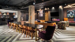 A modern lounge area with a large wooden table, comfortable seating, a fireplace, and a television. - Stylish Loft in St. Louis with Gym, Rooftop, Free Gated Parking, and Pool (St. Louis)