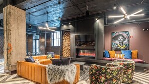 A modern lounge with a large sofa, ottomans, a fireplace, and a mural. - Stylish Loft in St. Louis with Gym, Rooftop, Free Gated Parking, and Pool (St. Louis)