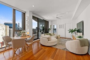 A modern living room with a large window, a dining area, and a seating area with a sofa and chairs.