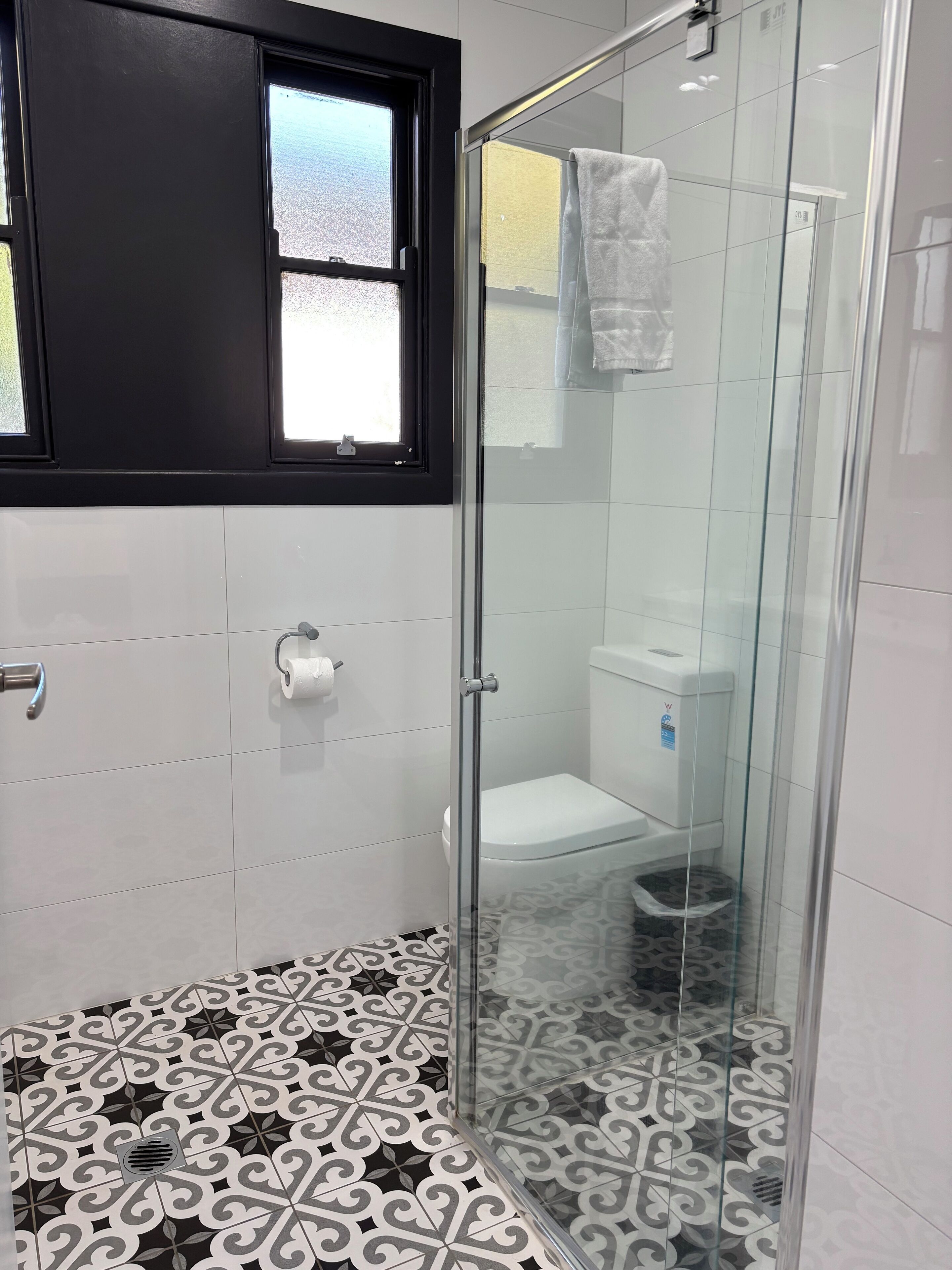 A bathroom with a shower, toilet, and a window.