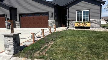 A modern two-story house with a stone foundation, a large garage, and a well-maintained lawn.