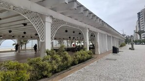 A covered walkway with arches, benches, and a view of the sea. - Apartment 2 Blocks from Guilhermina Beach-Praia Grande SP! Near Boqueirão (Praia Grande)