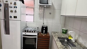 A compact kitchen with a refrigerator, microwave, stove, and sink. - Apartment 2 Blocks from Guilhermina Beach-Praia Grande SP! Near Boqueirão (Praia Grande)