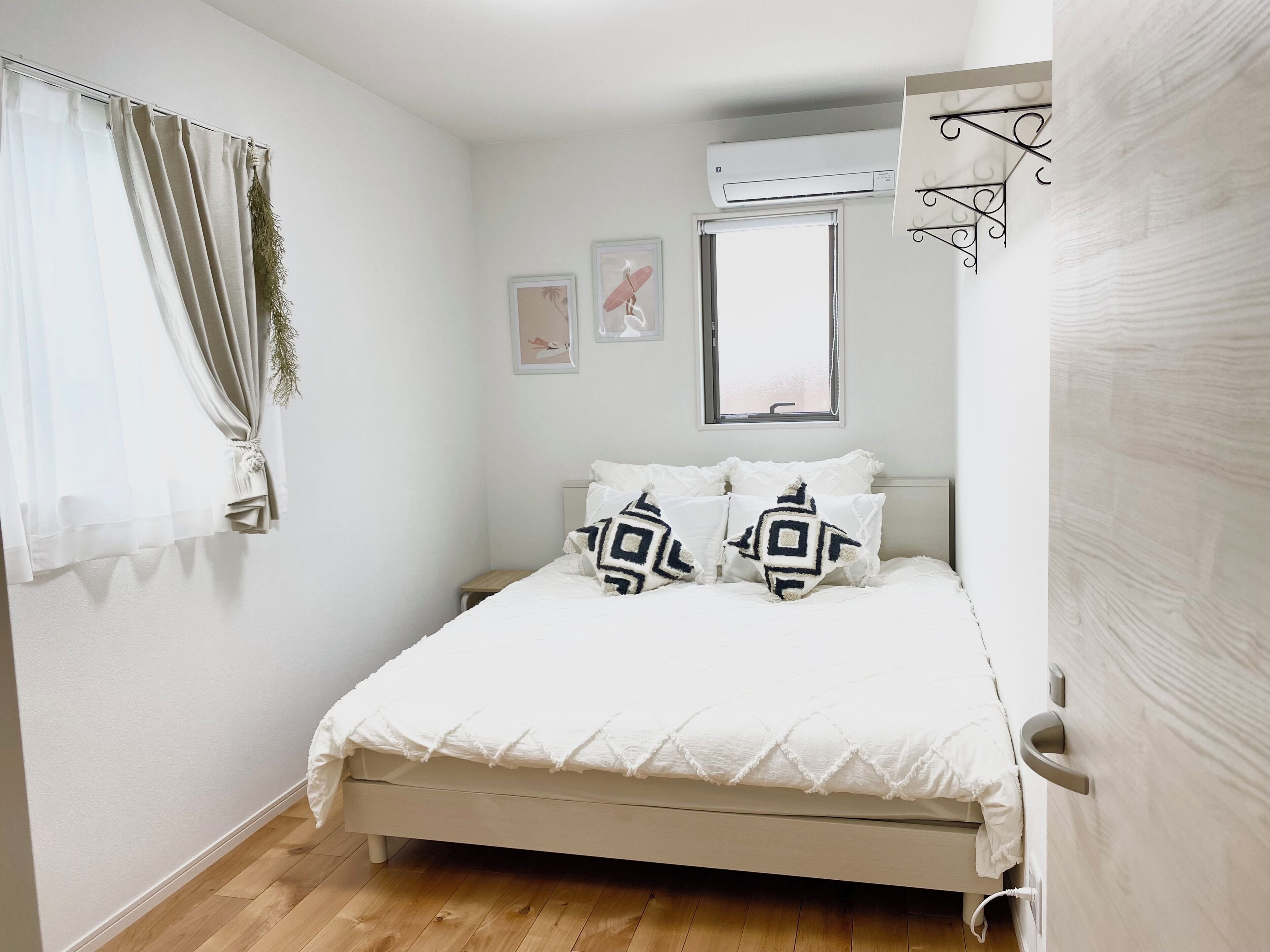 A bedroom with a bed, a window, an air conditioning unit, and a door.