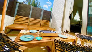 A wooden outdoor seating area with tables and chairs, a grill, and a view of the sky and trees. - New Onna | Cozy BBQ terrace, 8-min beach, snorkeling, SUP, sleeps 7, parking (恩納村)