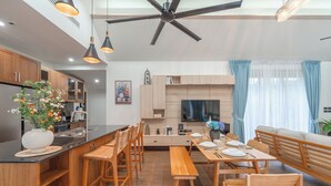 Eine moderne Küche mit Holzschränken, einer schwarzen Arbeitsplatte und einem Essbereich mit Holzmöbeln.