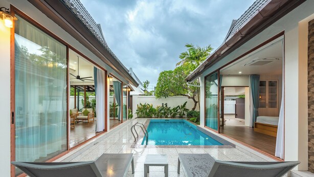 Ein modernes Haus mit Swimmingpool, Schiebegläsern und einer Terrassenanlage mit zwei Liegestühlen.