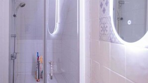 Ein Badezimmer mit Dusche, Waschbecken und Spiegel.