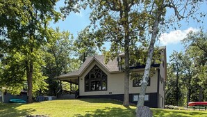 Ein Haus mit Teich im Vorgarten, umgeben von Bäumen und einer Anlegestelle.