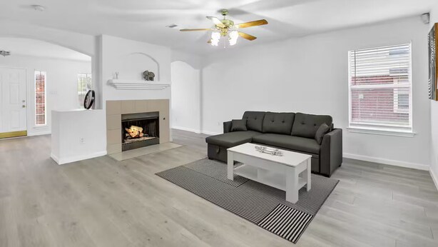 A modern living room with a fireplace, a black leather sofa, and a white coffee table.