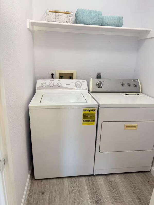 Un cuarto de lavandería con lavadora de carga frontal y secadora de carga superior.