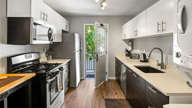 Una cocina moderna con electrodomésticos de acero inoxidable, un amplio ventanal y vistas al exterior.