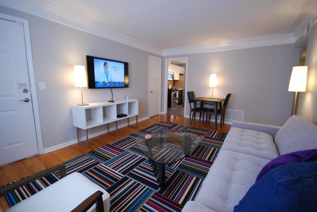 A modern living room with a sofa, a coffee table, a TV, and a patterned rug.