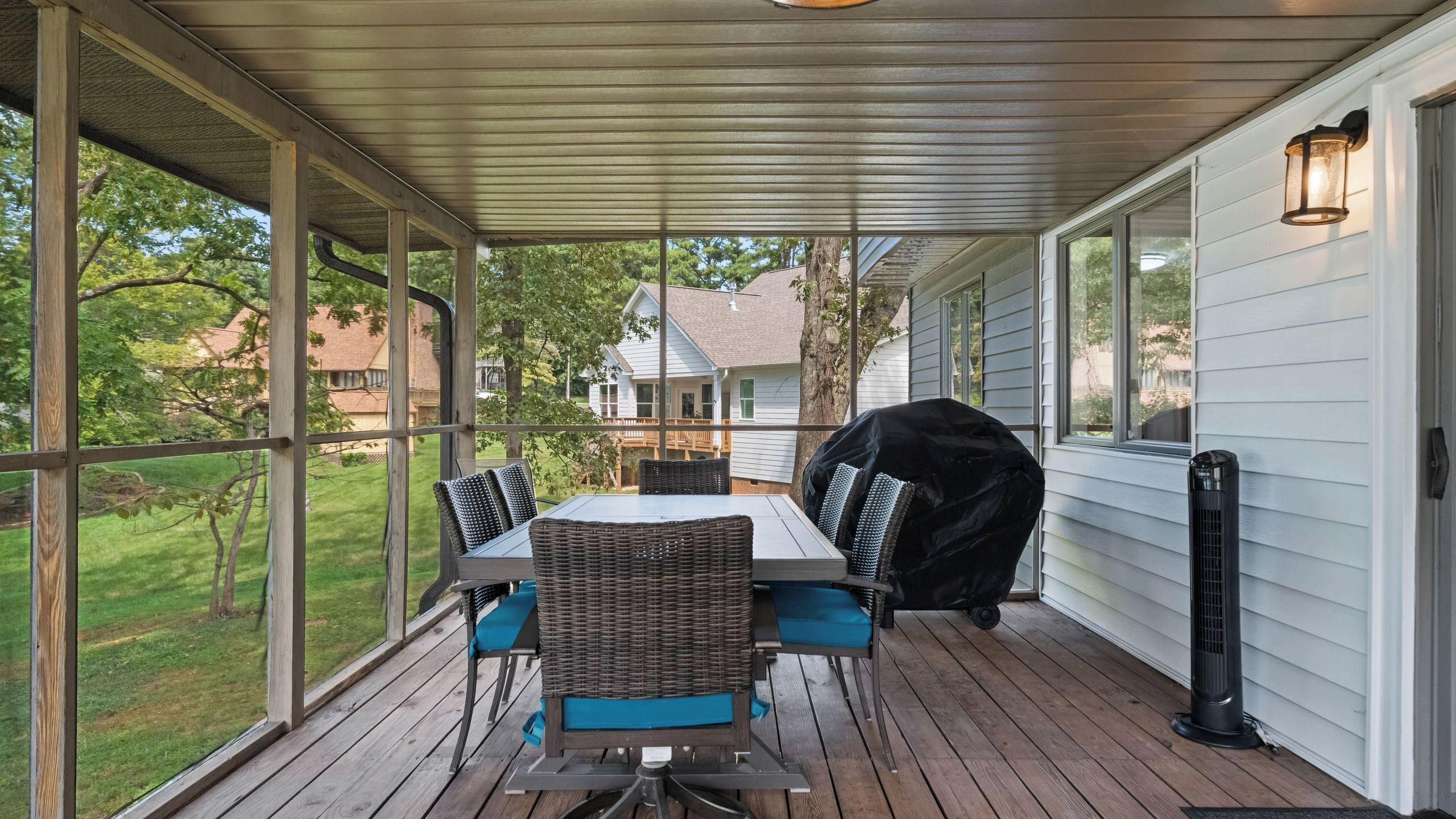 A covered patio with a table and chairs, a grill, and a heater.