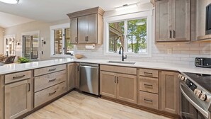 Una cucina moderna con mobili in legno, una lavastoviglie in acciaio inossidabile e un forno integrato.