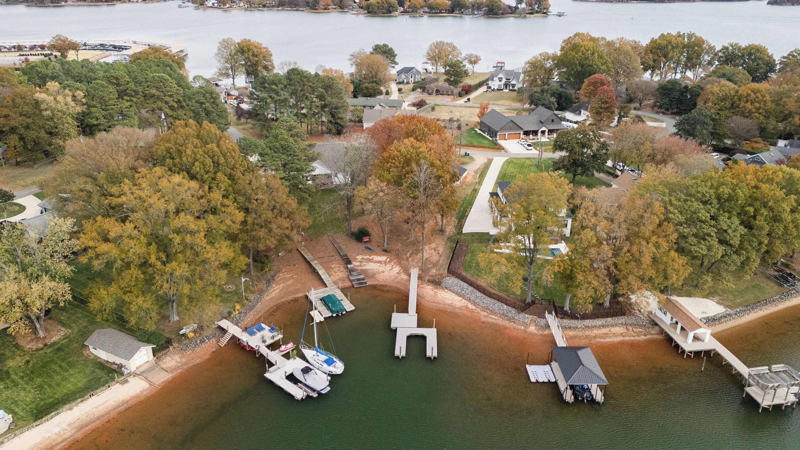 An aerial view of a lakeside property with a dock, boats, and houses.