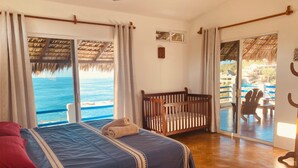 Un dormitorio con una cama, una cuna y vistas al océano.