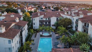 A residential area with a swimming pool surrounded by palm trees and a view of the ocean.