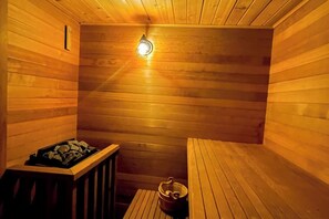 A wooden sauna with a bench, a small table, and a wall-mounted light fixture.