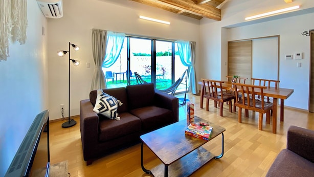 A living room with a sofa, coffee table, and dining area with chairs.