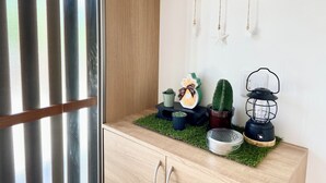 A room with a wooden cabinet, a cactus plant, a decorative item, and a lantern on a shelf.