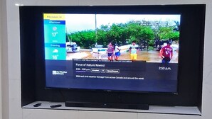 Un téléviseur à écran plat fixé à un mur blanc, avec une cheminée en dessous.