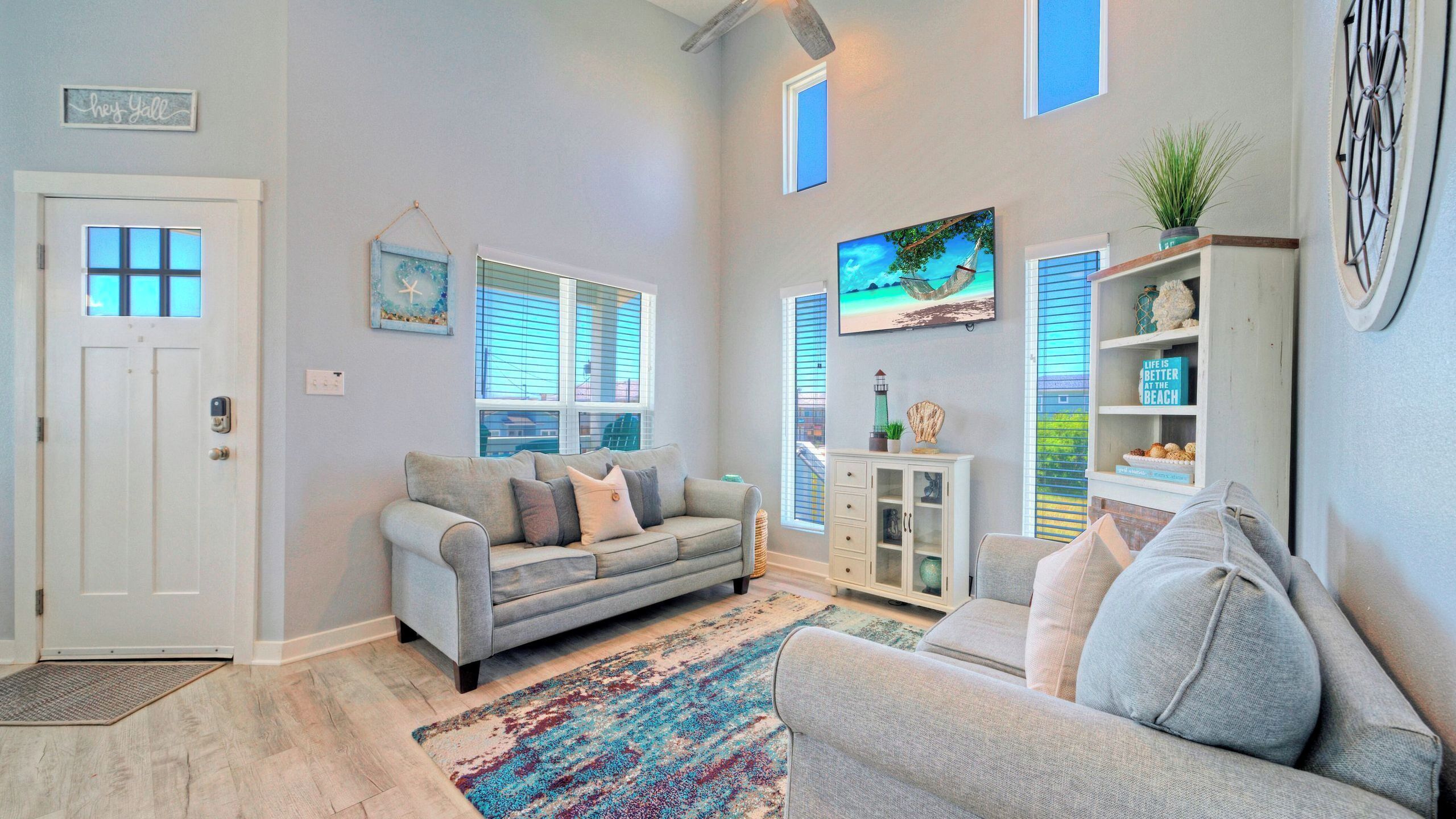 A living room with a grey sofa, a patterned rug, a bookshelf, and a painting on the wall.