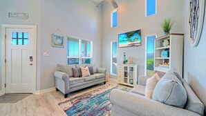 A living room with a grey sofa, a patterned rug, a bookshelf, and a painting on the wall.