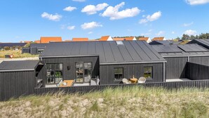 A modern building with a flat roof, large windows, and a patio area with outdoor furniture.