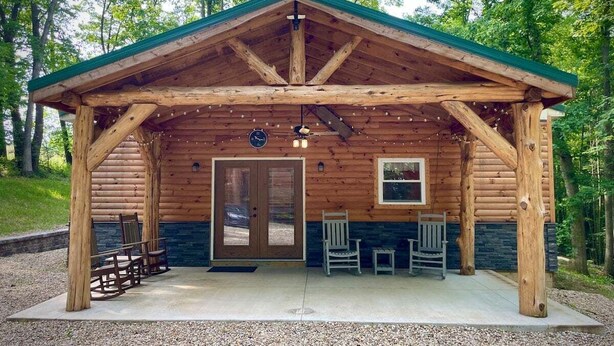 A wooden cabin with a covered porch, a door, and two windows.